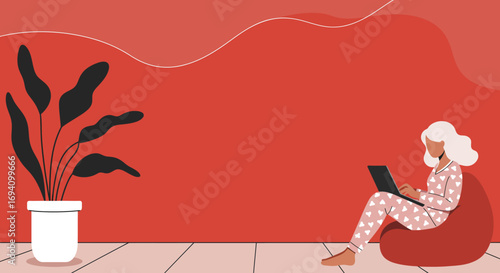 Woman in pajamas comfortably working on a laptop from a bean bag chair at home. Remote work, freelancing, and cozy lifestyle concept.