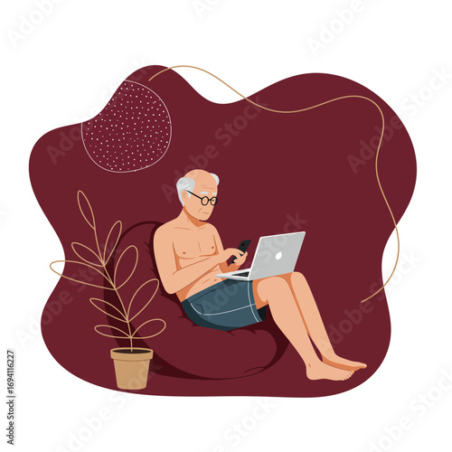 Relaxed senior man works from home, comfortably using a laptop and smartphone on a bean bag, enjoying modern connectivity.