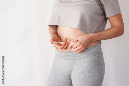 faceless woman giving herself an injection in her stomach. weight loss, diabetes