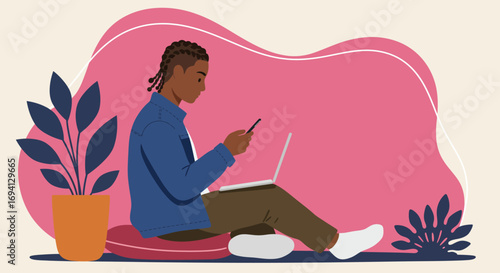 Young Black man with braids sits comfortably, engaged with a laptop and smartphone. Perfect for themes of remote work, online learning, digital communication, and modern lifestyle.