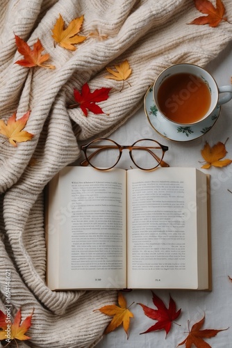 Rustic autumn scene with ceramic cup, reading glasses and open book on fabric
