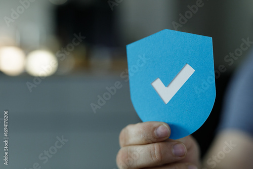 Bild auf Leinwand Image of a hand holding a blue shield with a checkmark, symbolizing security and approval