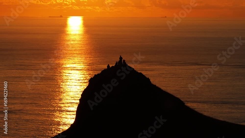 Aerial view of people on the mountain peak and watching the sunrise and ocean