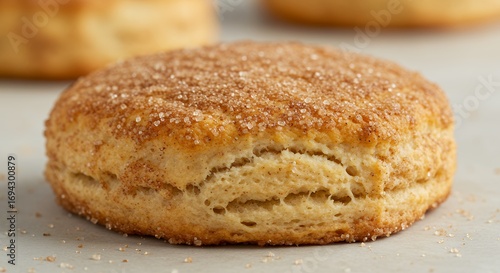 Close up view of a single biscuit with sugar crust on white surface