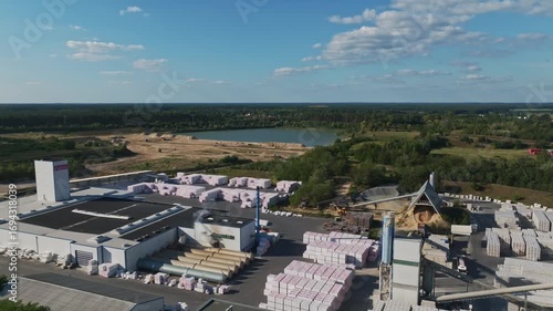 Aerial drone view of Baustoffwerke Havelland industrial factory in Oranienburg, Brandenburg, Germany, with storage of building materials and quarry lake in background. 15 September 2024