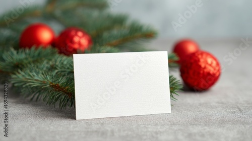 Blank card nestled among evergreen branches and vibrant red baubles, evoking Yule tidings and festive Nordic Jul celebrations
