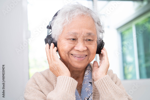 Asian senior woman patient happy to use earphone to listen relax music.
