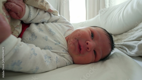 Bilde på lerret Newborn baby gesturing and moving under a blanket, grimacing with a curious expr
