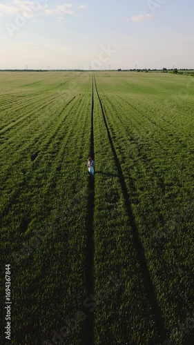 Aerial view of adult male farmer with tablet standing in green wheat field.