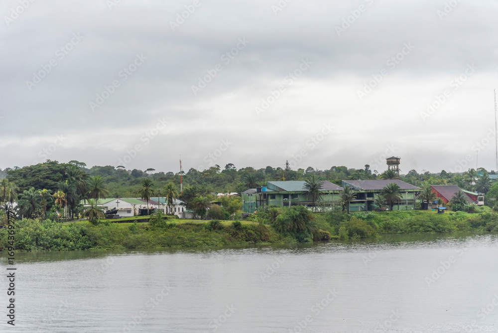 Fototapeta premium Village houses surrounded by tropical greenery along the riverbank near Buenaventura.