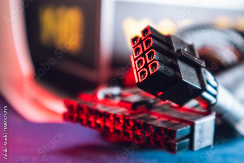 Cable connectors (8 and 24 pin) from power supply unit of desktop PC close-up. Computer wires in red light