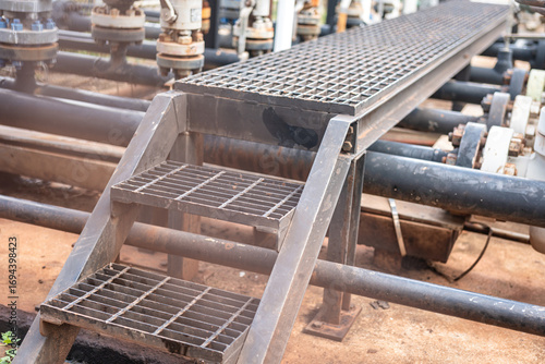 An overpass walkway across the production pipeline at the petrochemical and refinery plant. Industrial work place, close-up and selective focus.