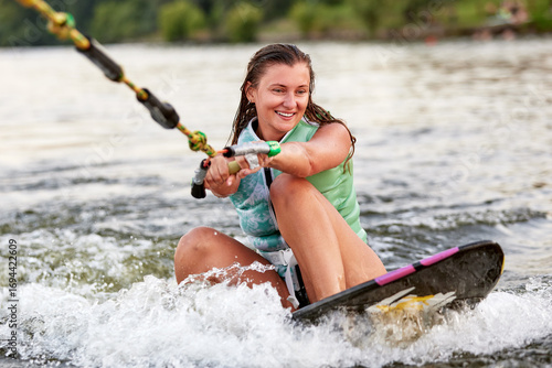Quadro su tela Young woman enjoying wakeboarding on a calm lake with joyful expression