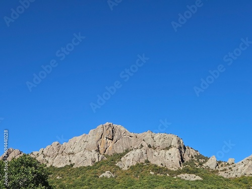 Majestic rocky mountain against a vast, clear blue sky. Perfect for travel themes, motivational content, or as a website banner with ample copy space for text.