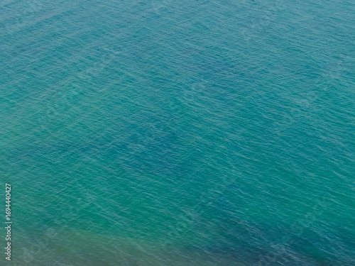 Aerial view of a calm, turquoise sea. A serene and minimalist background perfect for travel, wellness, or abstract design concepts.