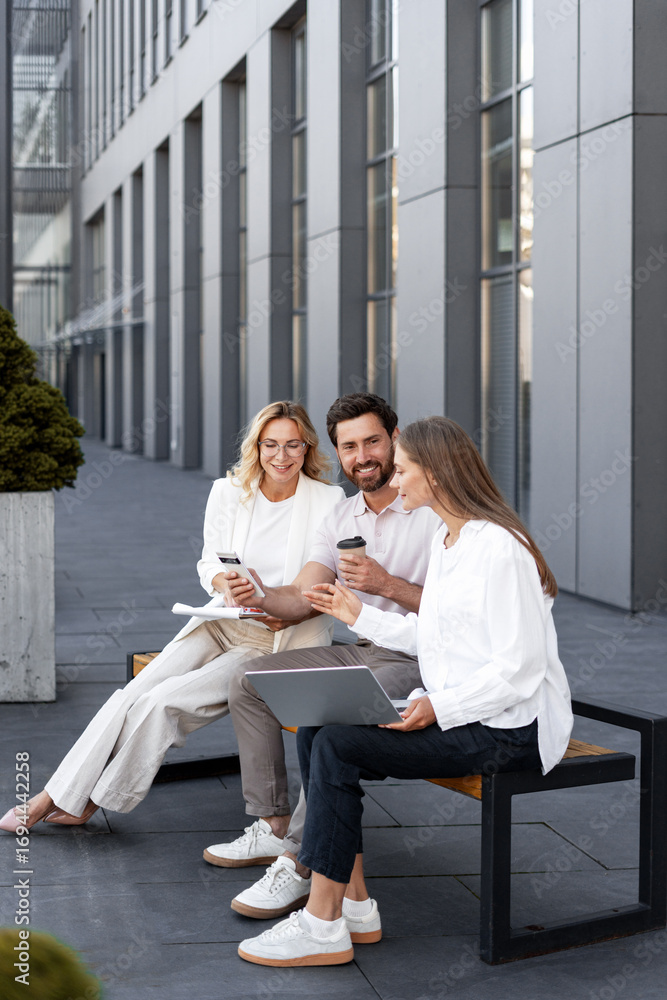 Fototapeta premium Businesspeople working together outdoors using laptop and smartphone