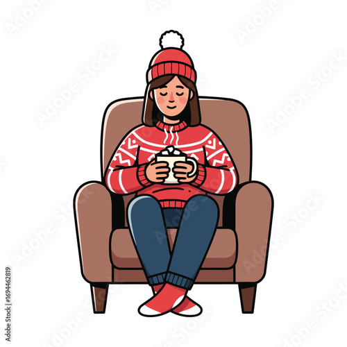 Woman in armchair with hot drink wearing winter clothes.
