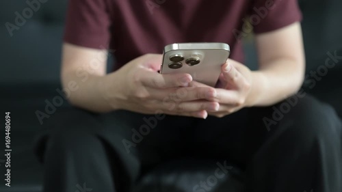 Close-up of happy young woman sitting on sofa at home texting and using mobile phone during day