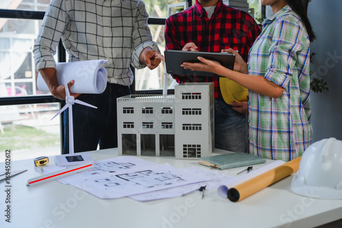 Architects analyzing sustainable building project with blueprints and 3d model