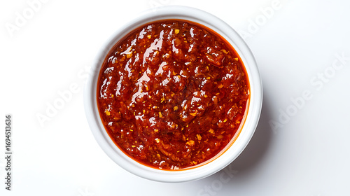 A bowl of red chili sauce on a white background shot from above view