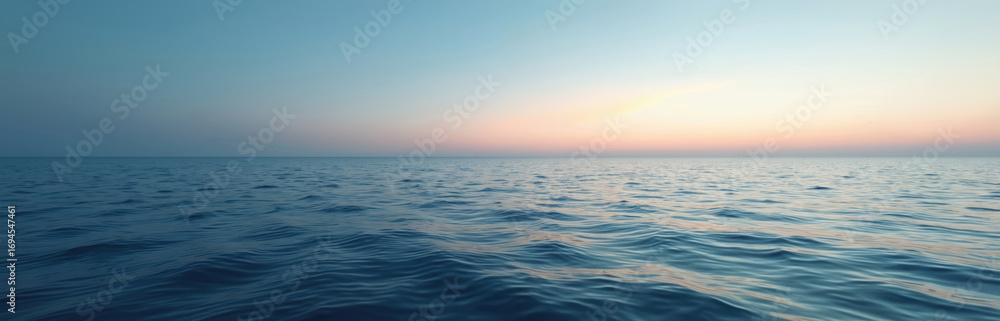 Fototapeta premium Calm ocean horizon at dusk with gentle waves. The clear sky shows soft colors from the setting sun. Tranquil seascape offers a sense of peace and serenity, perfect for relaxation or travel themes.
