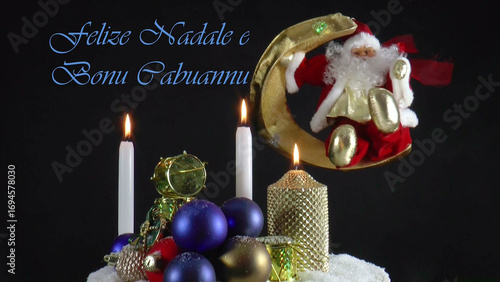 Warm Wishes for Christmas Joy 
A festive card with candles, baubles, and Santa Claus in the language Sardian
