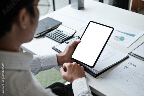 business person holding tablet with blank screen sitting at office desk during work