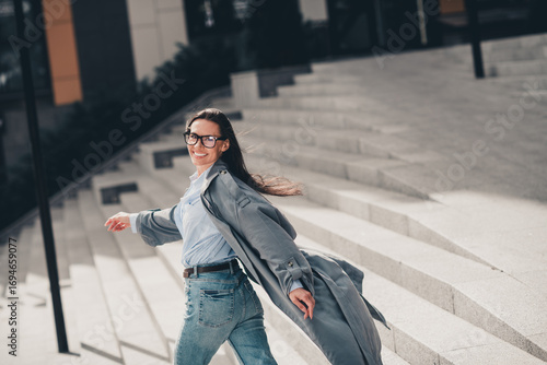 Stunning businesswoman in casual outfit enjoying a sunny day outdoors with a confident smile in an urban setting.