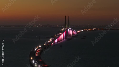 Highway road with driving traffic cars at night on Sunshine Skyway Bridge over Tampa Bay in Florida. Transportation infrastructure in USA