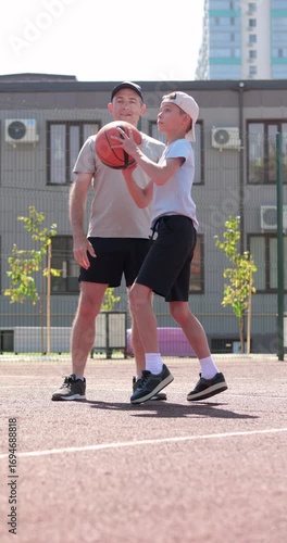 Vertical video child scores basketball goal with father. dad and child celebrate joyful moment. Father cheers son after shot. Family bonding on court, active family enjoying success together