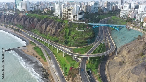 Aerial view of bridge la paz connecting miraflores district with the highway in lima, peru, featuring cars driving, buildings, and the pacific ocean