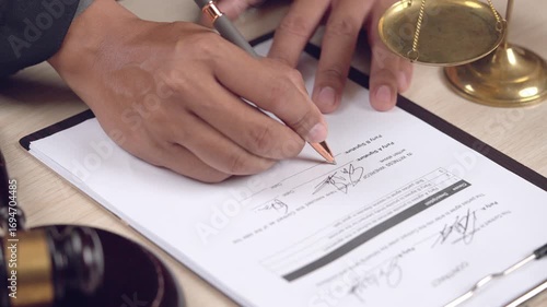 Official legal agreement being signed with visible justice scale and gavel. Ideal for law, court, or legal concept visuals.