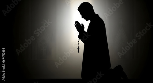Silhouette of a Man Praying on His Knees with a Rosary