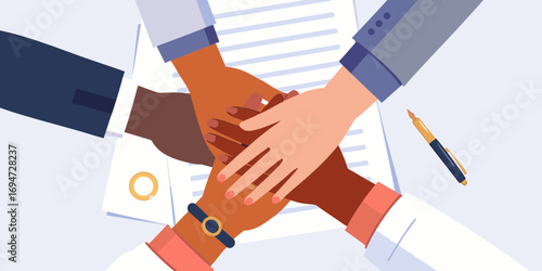 Diverse team of professionals stacking hands together in a gesture of unity and collaboration over documents