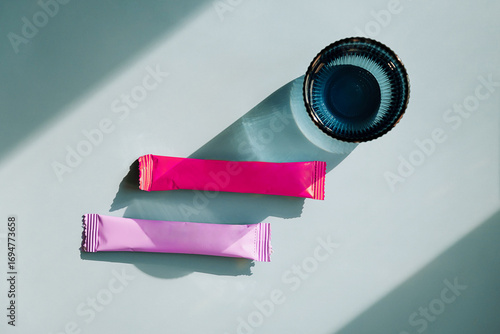 Two colorful sachets and blue glass with water on blue background.