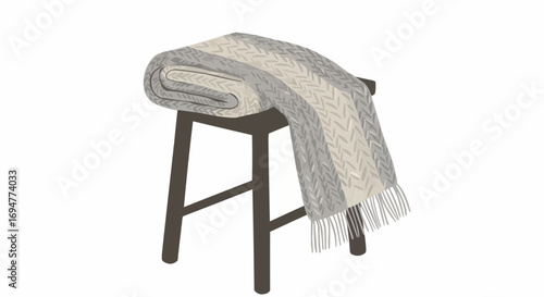 Cozy knitted blanket draped over a wooden stool in neutral tones  
