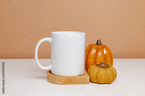 White mug mockup on ceramic cup coaster with pumpkins. Mockup coffee or tea mug for autumn design, gift, logo or print
