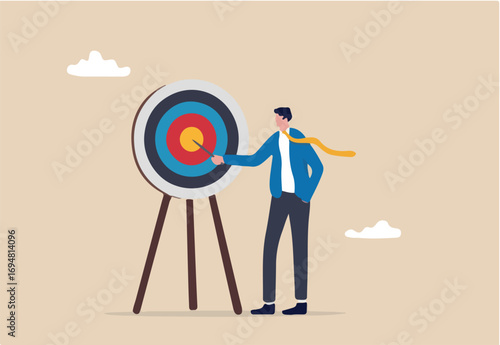 Specific goal, clarify objective or target, focus or concentrate on purpose to win business mission, perfection or aiming at target concept, businessman pointing at center of bullseye archery target. 
