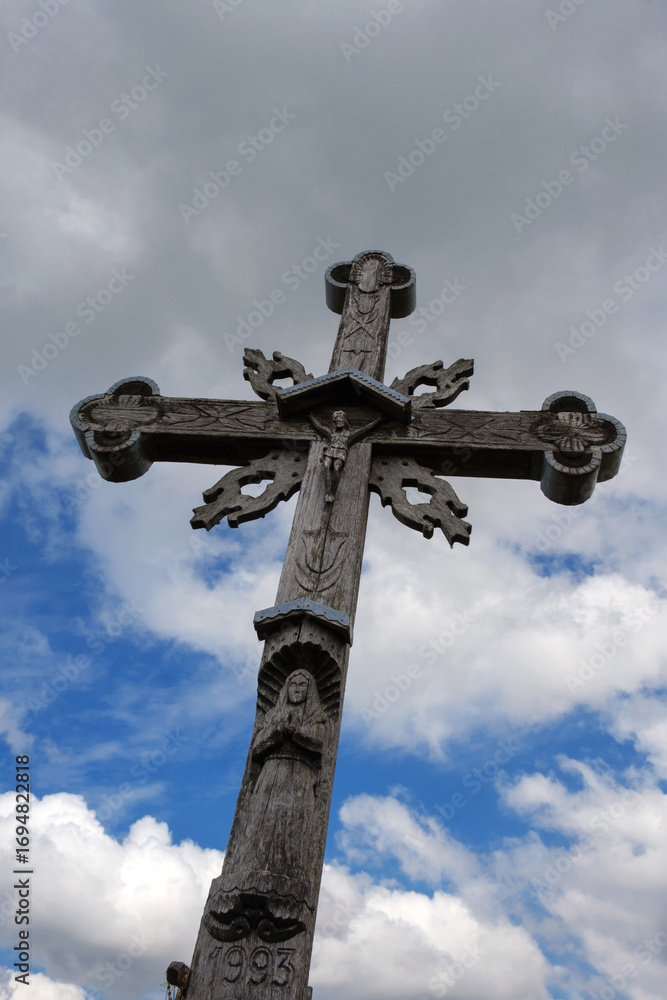 Old wooden cross on a blue cloudy sky background Old wooden cross on a blue cloudy sky background