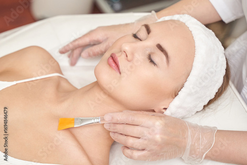 Female adult caucasian receiving facial mask treatment at spa with relaxed expression and spa headband.