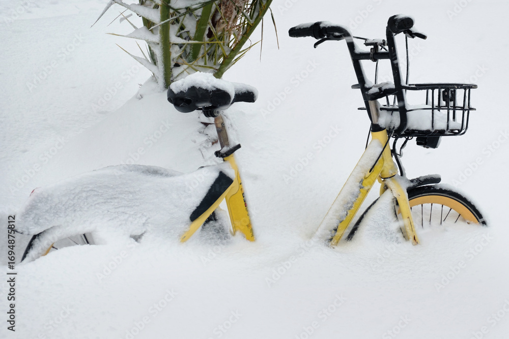 Fototapeta premium Yellow bicycle parked in deep snow
