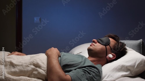 The man puts a sleep mask on his face and plugs his ears with earplugs