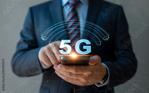 Businessman utilizing smartphone technology with glowing 5g hologram and futuristic connection signals