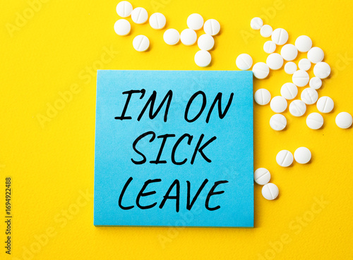 Sick leave symbol. Concept word I am on sick leave on blue note. Beautiful yellow background with pills. Medicine and I am on sick leave concept. Copy space