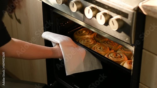 Female hands take out baking pan with buns from oven. Baking cinnamon rolls with apple filling. Dessert baking recipes