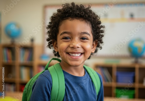 Smiling boy in a classroom with a backpack