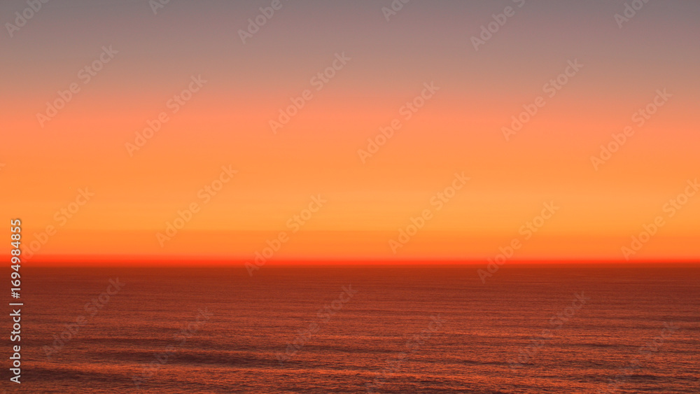Obraz premium Reddish-orange sunset over the Atlantic Ocean.