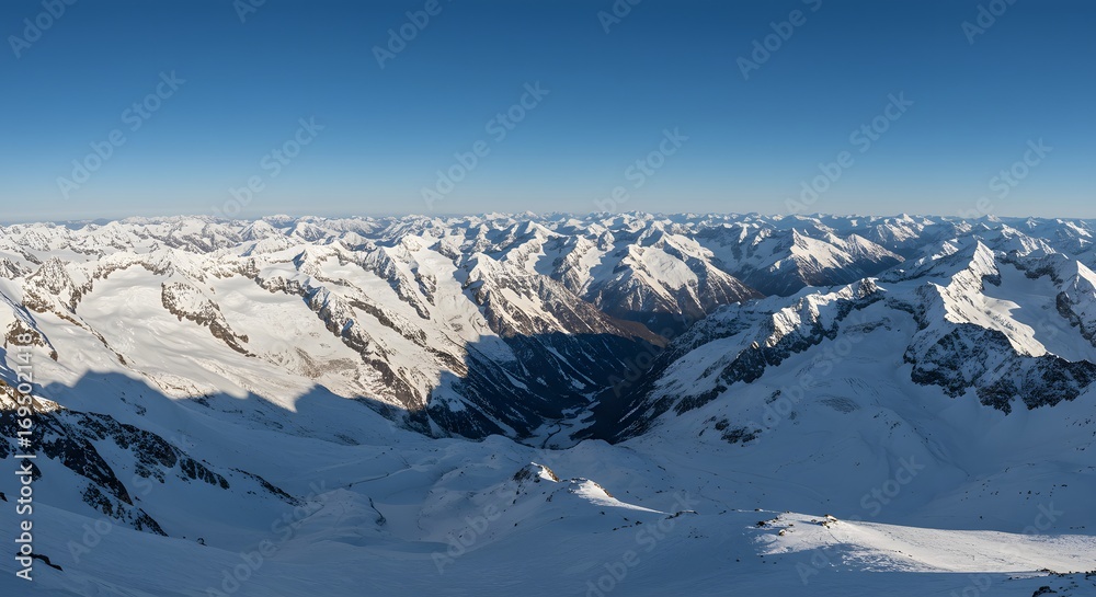 Obraz premium Aerial view of snow covered mountain range under a clear blue sky on a bright sunny day landscape scene