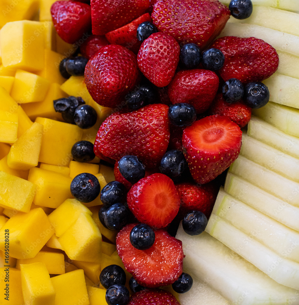 Obraz premium Mixed fresh fruits: strawberries, blueberries, mango, and melon.