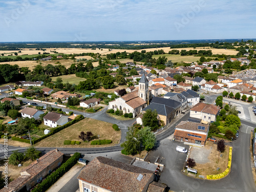 Photo aérienne de Eglise Saint Gervais Saint Protais à Champagné-Saint-Hilaire. Vue de la partie est de l'église (le choeur) et du clocher carré. En arrière plan les maisons du village et la campagne.